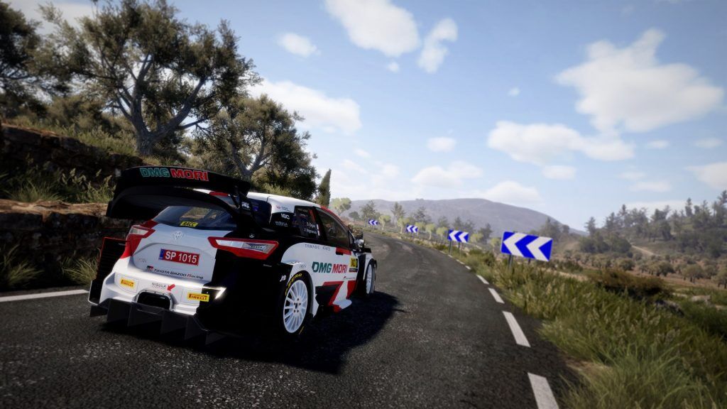An image of a Toyota rally car in WRC 10. On the right, there are road signs with arrows pointing around an upcoming bend.