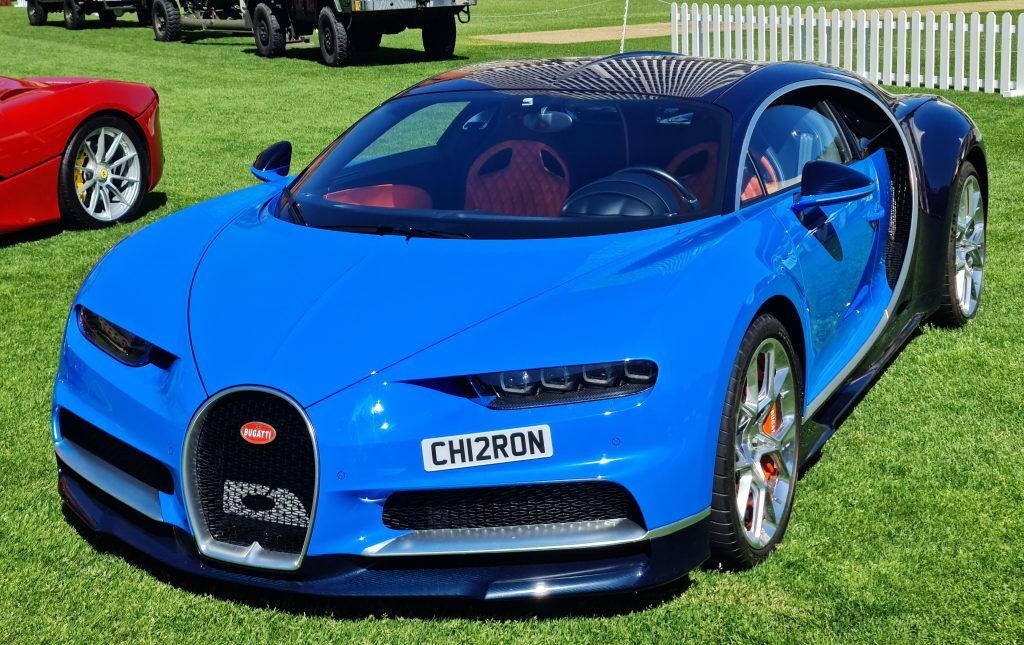 A primarily blue and secondarily black Bugatti Chiron parked on grass.