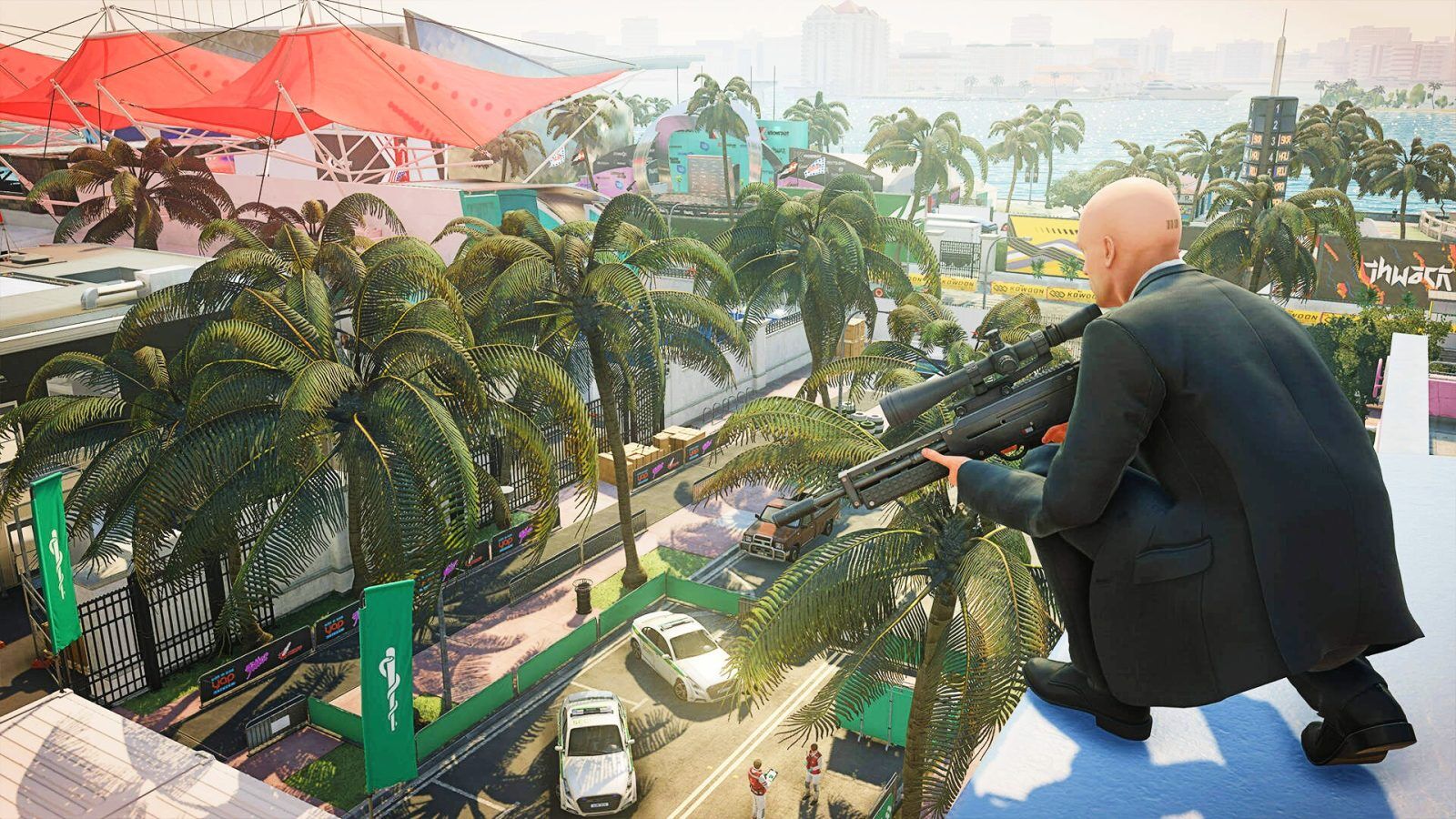 Hitman Agent 47 crouching on a roof overlooking a street circuit.