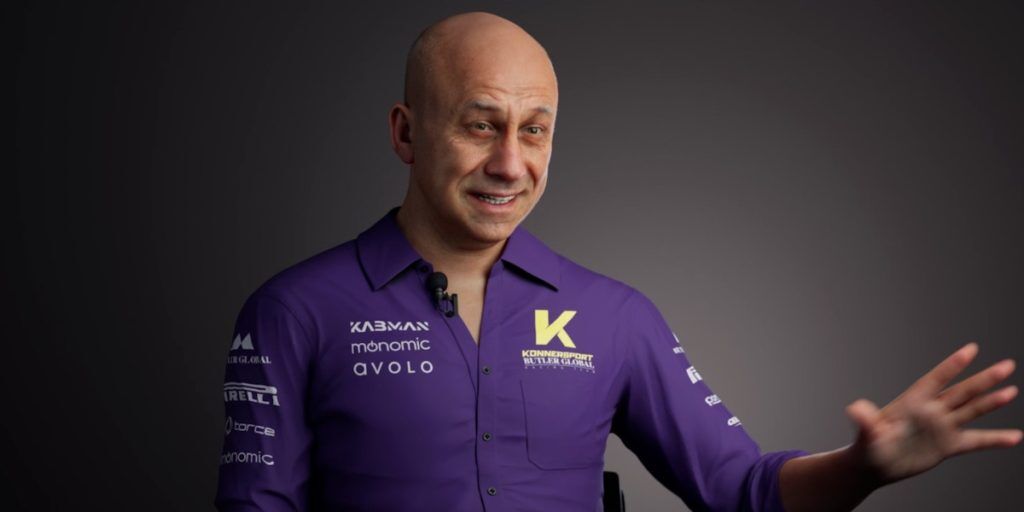 A man in a purple button shirt with a yellow K on it.
