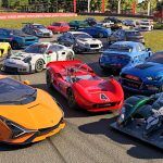 A huge collection of exotic cars parked on a racetrack.