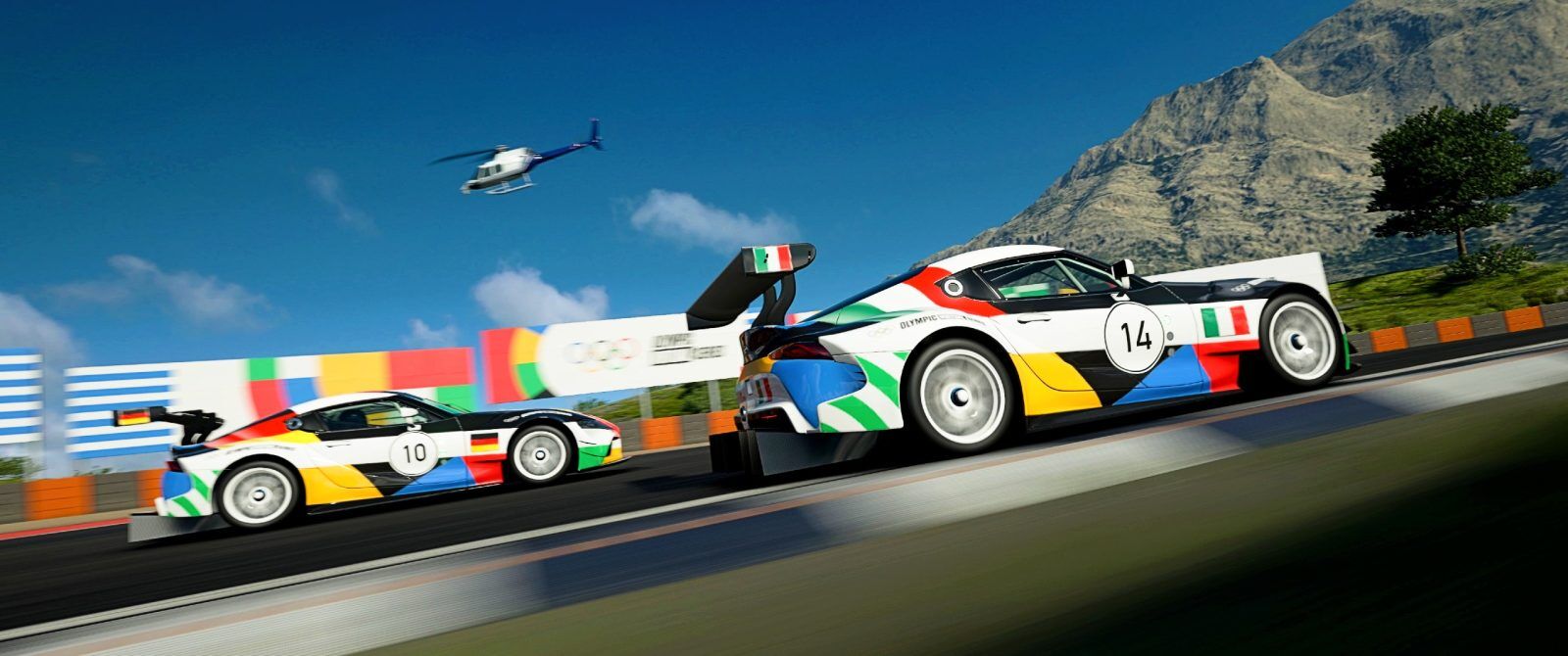 Two Toyota Supra racecars in Olympic colours, one with an Italian flag and one with a German flag.