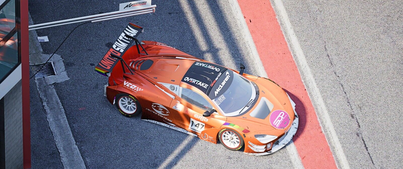 A metallic orange and chrome red McLaren racing car in a pit stall.