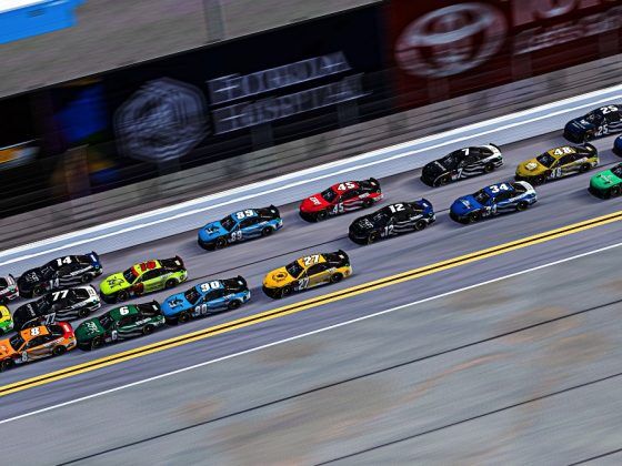 A line of NASCAR stock cars racing.